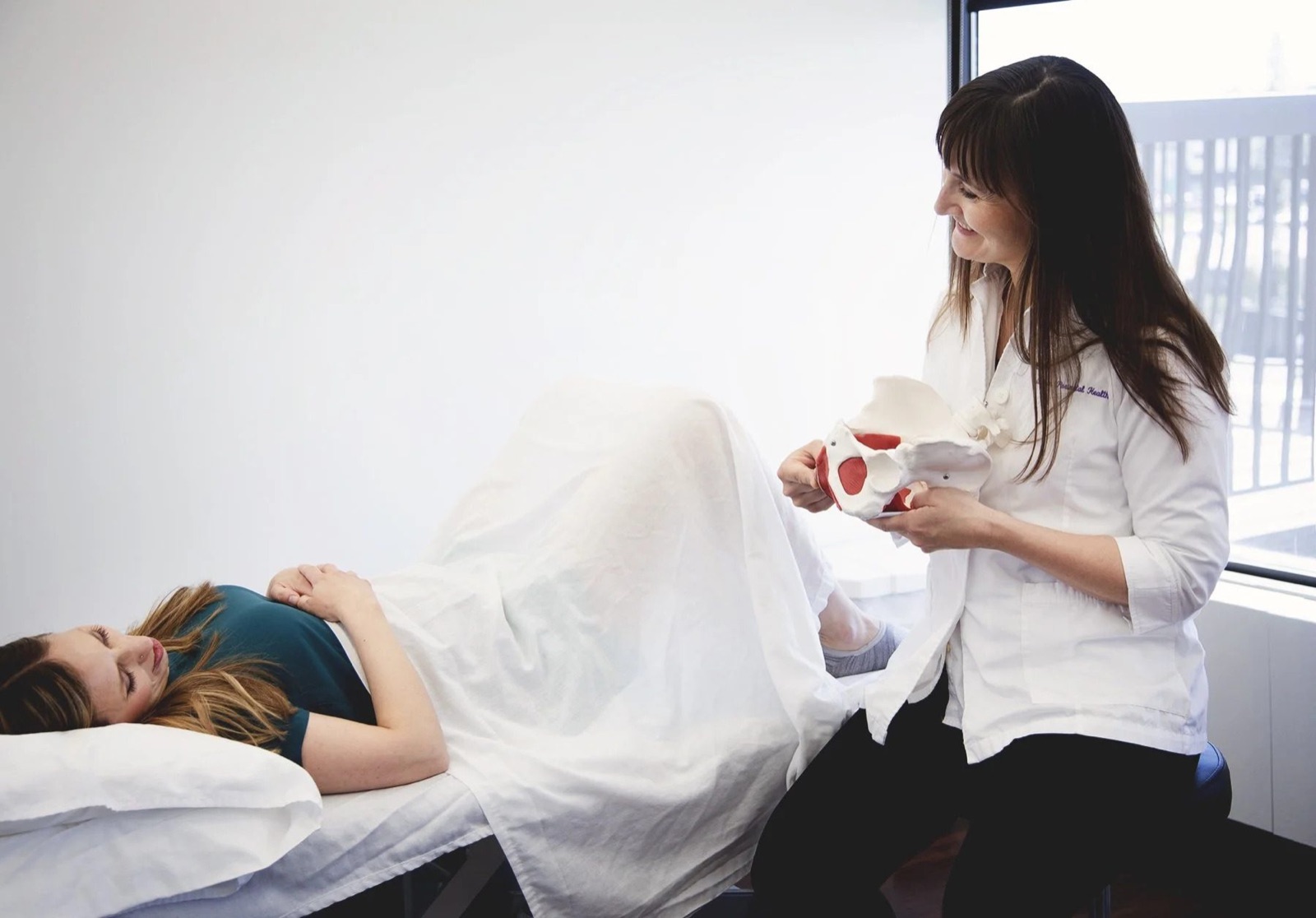 A physiotherapist explaining pessary options using a pelvic model
