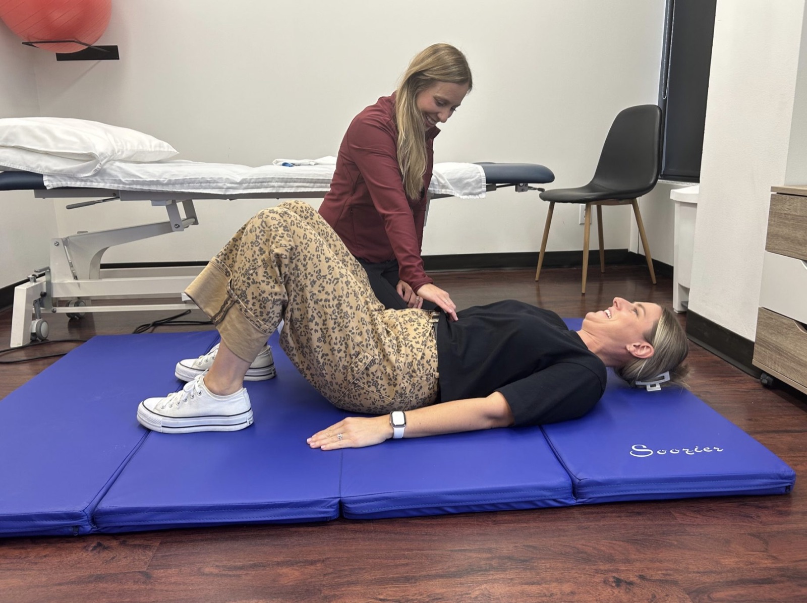 An Optimum physiotherapist cueing a client through pelvic floor exercise on a mat